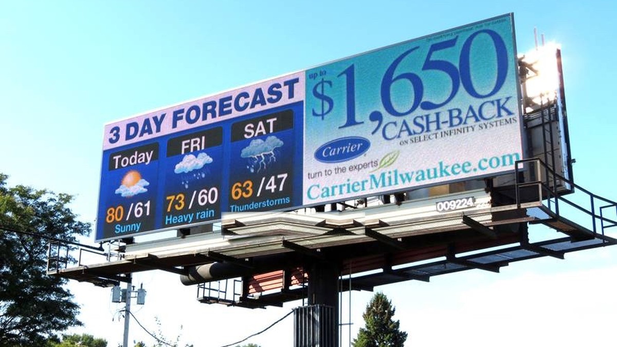 Clear Channel digital billboard in Milwaukee showing a 3-day weather forecast alongside a Carrier HVAC cash-back ad